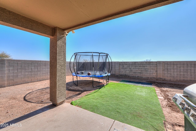 view of yard with a trampoline and a patio area