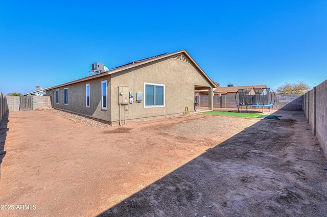 5175 W Warren Dr, Casa Grande, AZ 85194 - rear view of house featuring cooling unit, a trampoline, stucco siding, and a fenced backyard