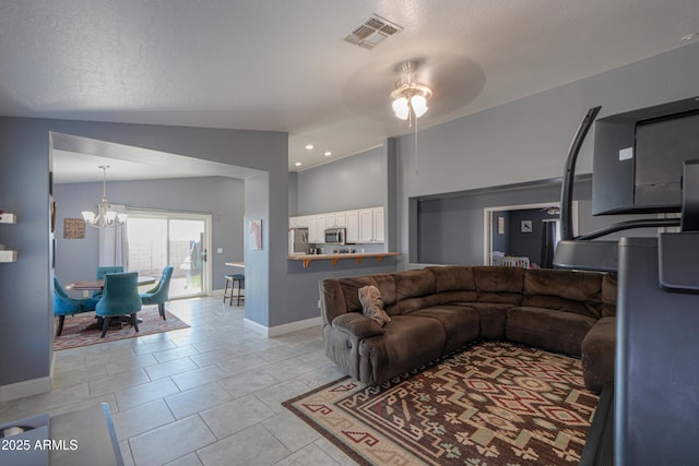 living room featuring ceiling fan with notable chandelier, lofted ceiling, light tile patterned floors, and a textured ceiling