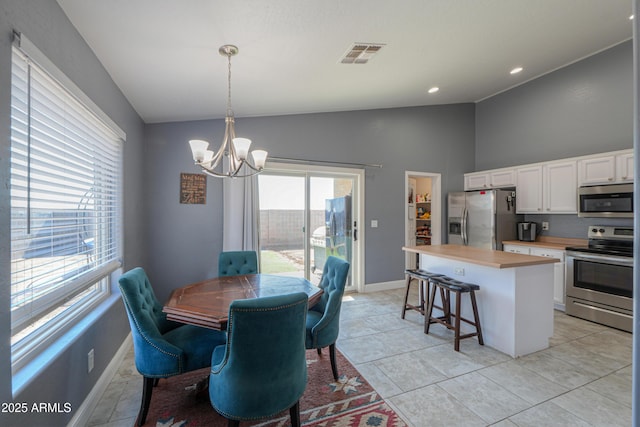 tiled dining area with an inviting chandelier and vaulted ceiling