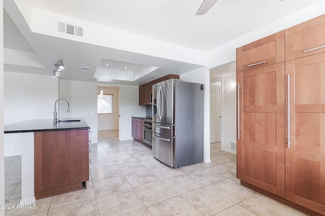 kitchen with light tile patterned flooring, sink, stainless steel appliances, and a tray ceiling