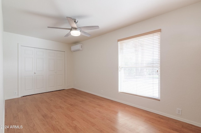 unfurnished bedroom featuring an AC wall unit, ceiling fan, a closet, and light wood-type flooring