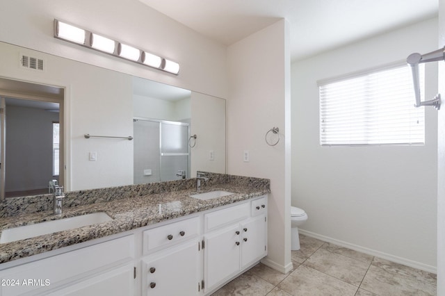 bathroom featuring tile patterned flooring, vanity, toilet, and a shower with door