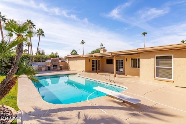 view of swimming pool with a patio, a diving board, and an outdoor fireplace