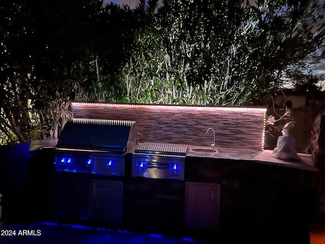 patio at night featuring a grill and sink