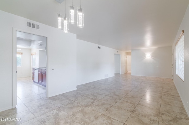 empty room with a healthy amount of sunlight and light tile patterned floors