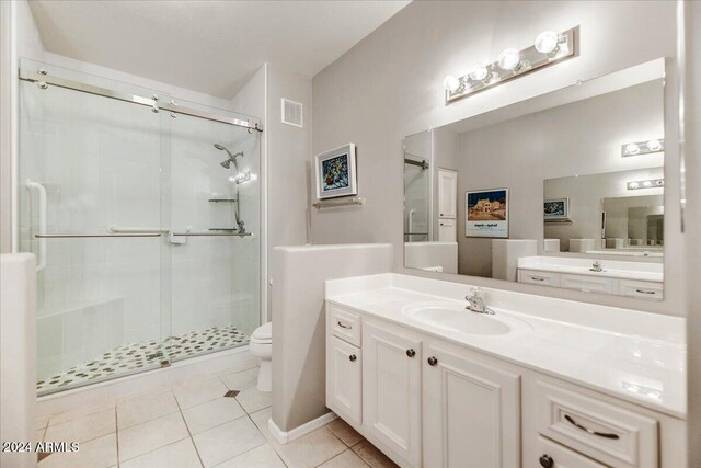 bathroom with vanity, walk in shower, toilet, and tile patterned floors