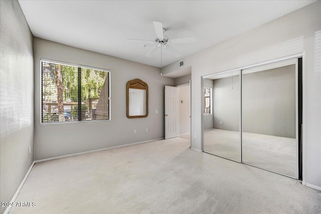 unfurnished bedroom with a closet, light colored carpet, and ceiling fan