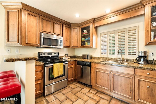8638 E Paraiso Dr, Scottsdale, AZ 85255 - kitchen with brown cabinetry, dark stone counters, brick floor, a sink, and stainless steel appliances
