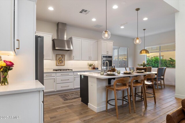 5661 S Dante, Mesa, AZ 85212 - kitchen featuring wall chimney range hood, appliances with stainless steel finishes, white cabinets, wood finished floors, and recessed lighting