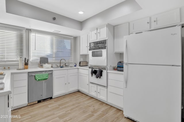 kitchen with light hardwood / wood-style floors, white cabinetry, white appliances, and sink