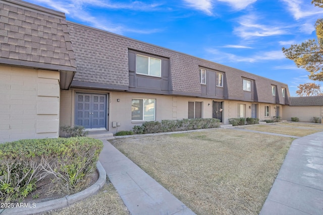 townhome / multi-family property featuring a front lawn