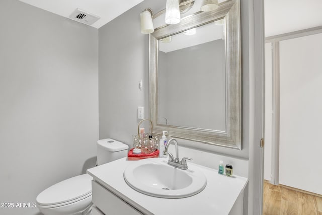 bathroom with vanity, toilet, and wood-type flooring