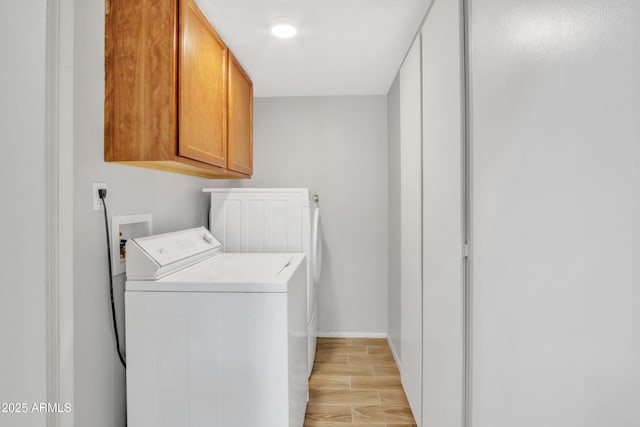 clothes washing area with light hardwood / wood-style flooring, cabinets, and independent washer and dryer