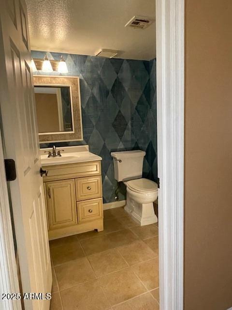 bathroom featuring tile patterned flooring, vanity, a textured ceiling, and toilet