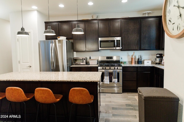14344 W Hackamore Dr, Surprise, AZ 85387 - kitchen with stainless steel appliances, a kitchen bar, dark brown cabinets, recessed lighting, and hanging light fixtures