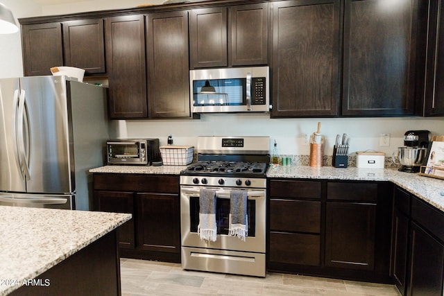 14344 W Hackamore Dr, Surprise, AZ 85387 - kitchen featuring stainless steel appliances, dark brown cabinets, light stone countertops, and light wood finished floors