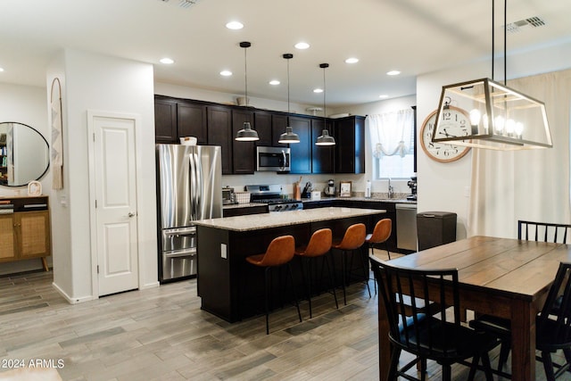 14344 W Hackamore Dr, Surprise, AZ 85387 - kitchen featuring appliances with stainless steel finishes, a center island, light wood finished floors, recessed lighting, and decorative light fixtures
