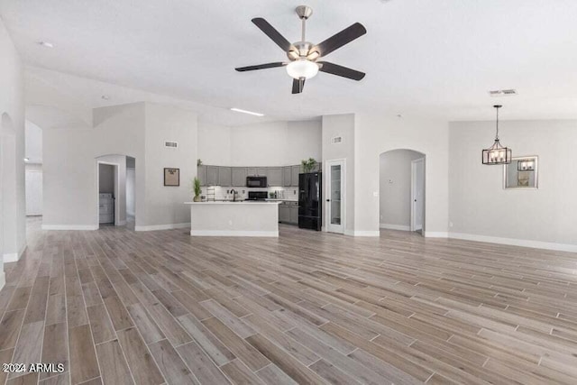 unfurnished living room with a towering ceiling, light hardwood / wood-style floors, and ceiling fan