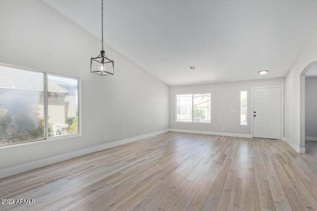 unfurnished living room featuring a healthy amount of sunlight, light wood-type flooring, and vaulted ceiling