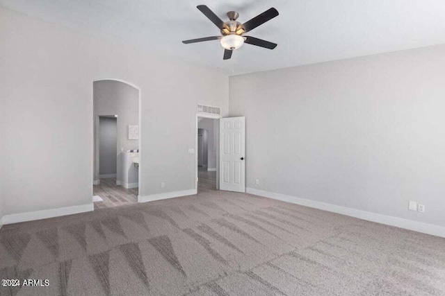 unfurnished bedroom with ceiling fan, ensuite bathroom, and light colored carpet