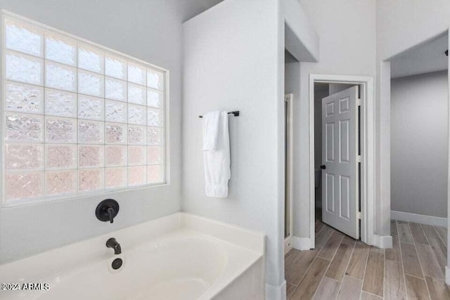 bathroom featuring a tub to relax in, plenty of natural light, and hardwood / wood-style floors