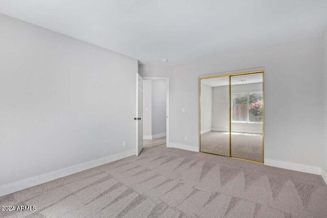 unfurnished bedroom with a closet and light colored carpet