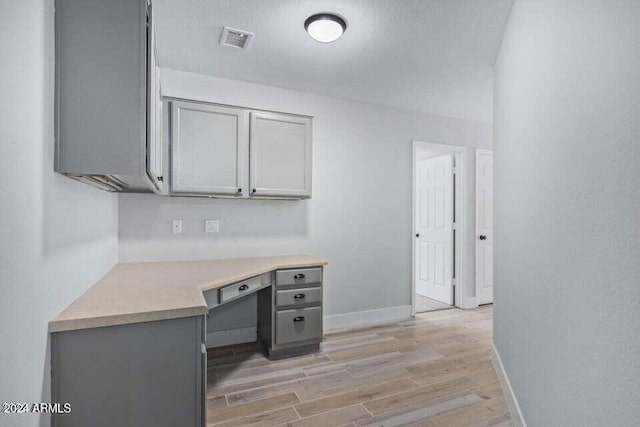 unfurnished office featuring built in desk and light wood-type flooring