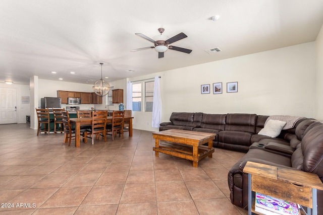 tiled living room featuring ceiling fan with notable chandelier