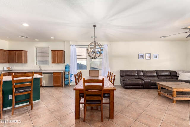 tiled dining room with ceiling fan with notable chandelier and sink