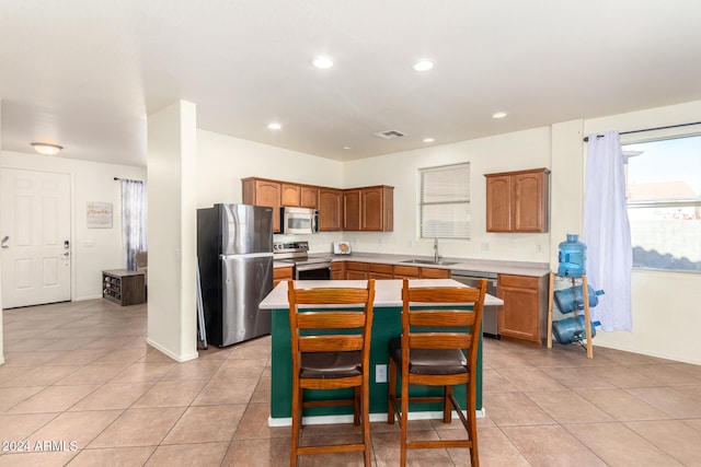 kitchen featuring a center island, light tile patterned floors, sink, and stainless steel appliances