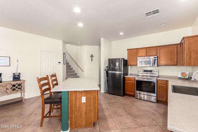 kitchen with a breakfast bar, sink, appliances with stainless steel finishes, and tile patterned flooring