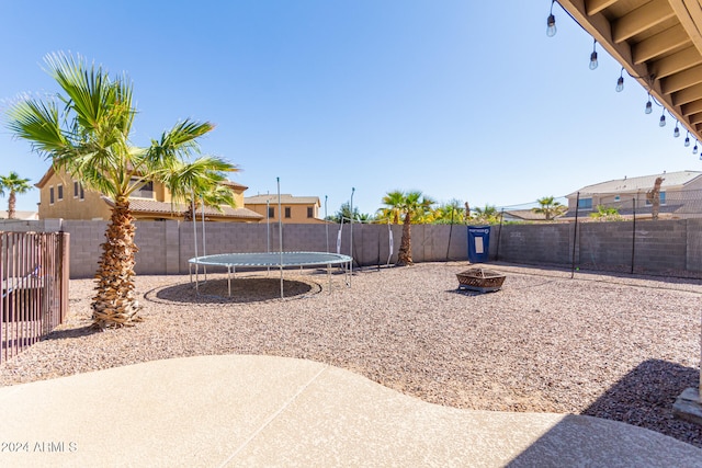 view of yard featuring a trampoline and a fire pit