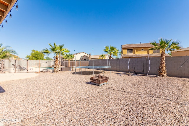 view of yard featuring a trampoline, an outdoor fire pit, and a patio area