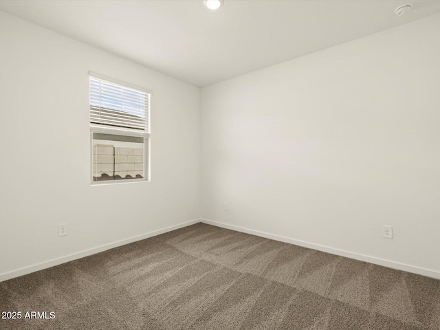 unfurnished room featuring dark colored carpet and baseboards