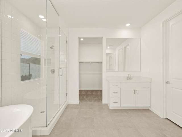bathroom featuring a shower stall, a freestanding tub, vanity, a walk in closet, and recessed lighting