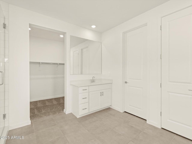 bathroom featuring recessed lighting, a stall shower, a spacious closet, vanity, and baseboards