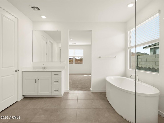 full bath featuring a freestanding bath, vanity, recessed lighting, baseboards, and tile patterned floors
