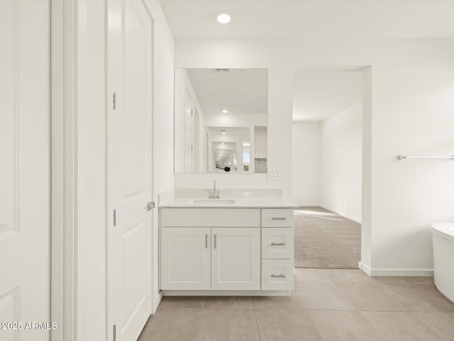 bathroom with tile patterned flooring, vanity, a freestanding bath, baseboards, and recessed lighting