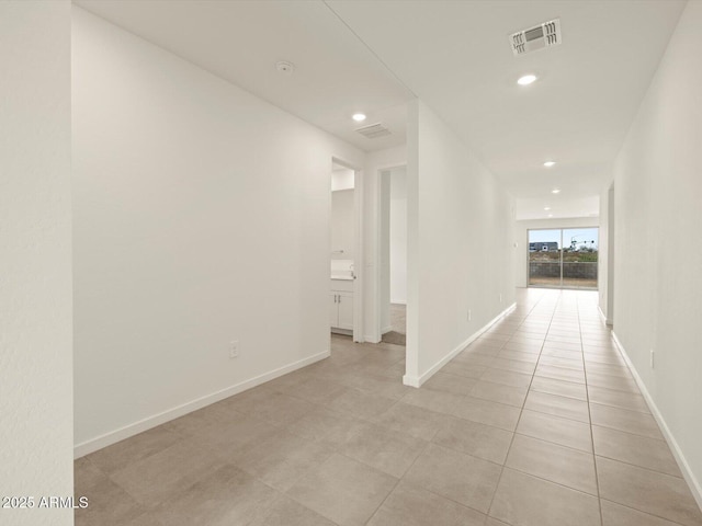 hallway featuring baseboards, recessed lighting, and light tile patterned floors