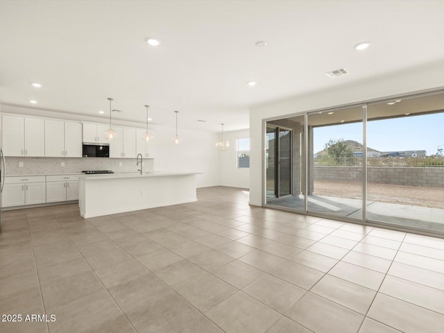kitchen with stainless steel microwave, decorative backsplash, recessed lighting, light countertops, and light tile patterned flooring