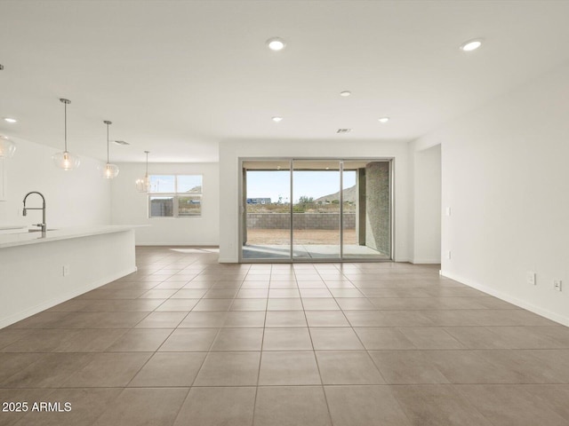 unfurnished living room featuring recessed lighting, tile patterned flooring, baseboards, and a sink