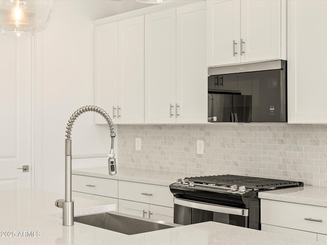 kitchen with stainless steel appliances, white cabinetry, a sink, and tasteful backsplash