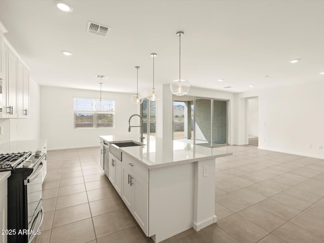 kitchen with light tile patterned flooring, a sink, visible vents, white cabinets, and gas stove