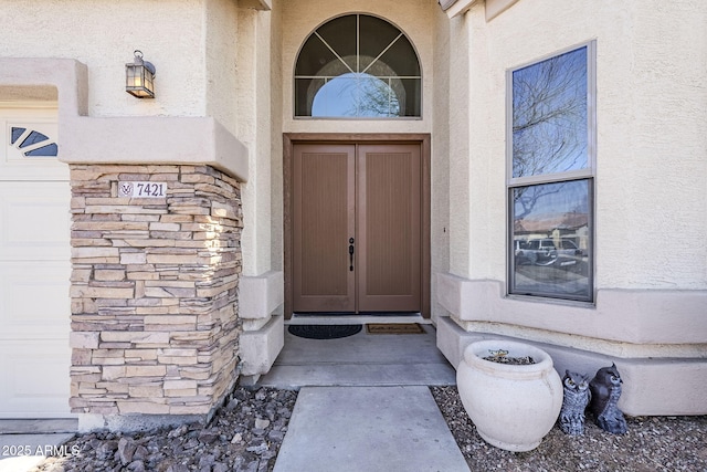 property entrance featuring a garage and stucco siding