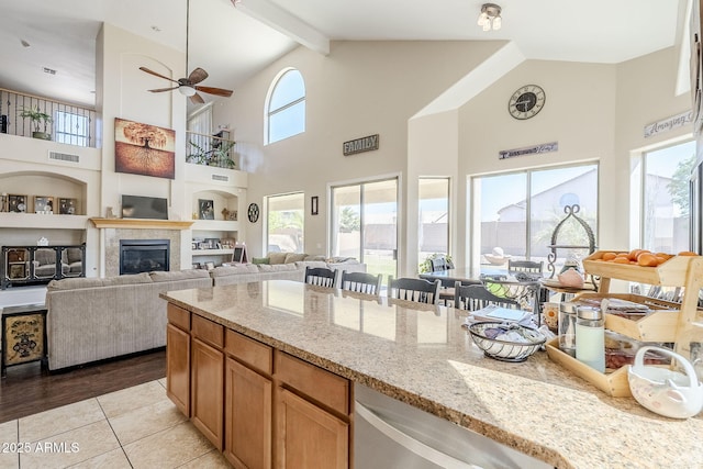 kitchen with visible vents, a glass covered fireplace, light stone countertops, built in shelves, and beam ceiling