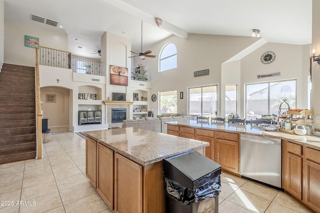 kitchen with light tile patterned flooring, visible vents, stainless steel dishwasher, and a glass covered fireplace