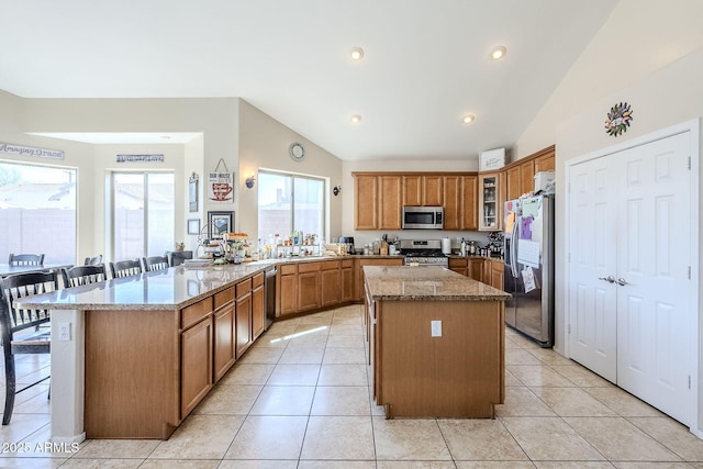 kitchen with brown cabinets, a peninsula, stainless steel appliances, and lofted ceiling