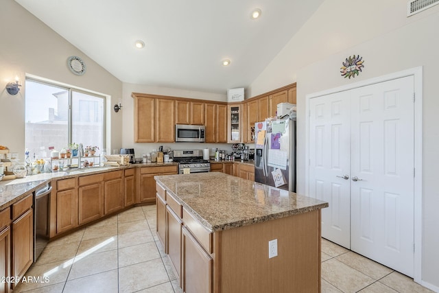 kitchen with visible vents, a center island, light stone countertops, vaulted ceiling, and stainless steel appliances