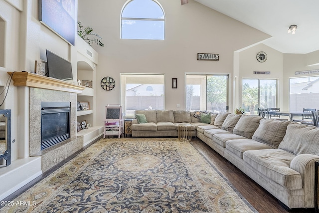 living area featuring plenty of natural light, a fireplace, built in features, and wood finished floors